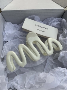 Detailed view of large cream wavy hair claw clip in aesthetic minimalist packaging