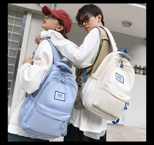 Close-up of sky blue and off-white canvas backpacks featuring multi-layer storage pockets
