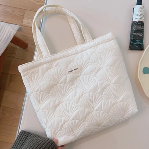 Detail view of the white quilted tote bag featuring shell stitching and simple wish label