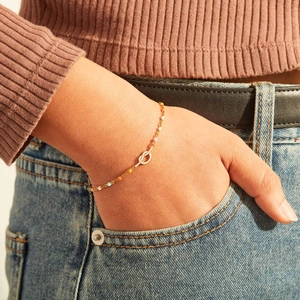 Chic gold knot bracelet with colorful enamel beads worn on a model's wrist