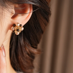 Gros plan de boucles d'oreilles fleurs dorées et perles portées par un mannequin