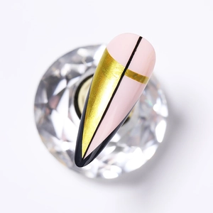 Detailed view of pointed nail tip with black gold and pink geometric block design