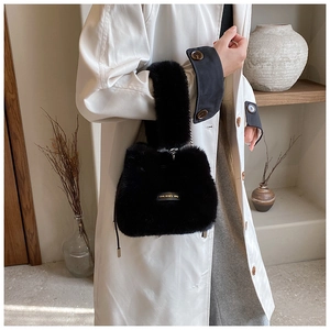 Detail of plush bucket bag with silver chain and love every day tag on white trench coat