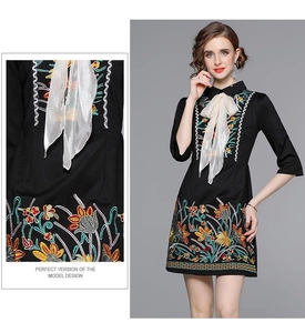 Detail of colorful floral embroidery and bow tie neckline on black midi dress