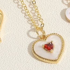 Macro view of heart-shaped marble pendant necklace with central red zircon stone