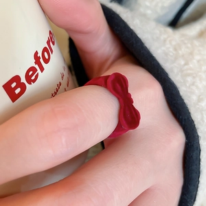 Close-up of a red flocked velvet bow ring on finger with a cozy vintage aesthetic