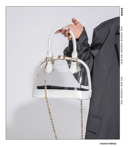 Detailed view of a transparent PVC shell bag with pearl white trim and gold chain strap