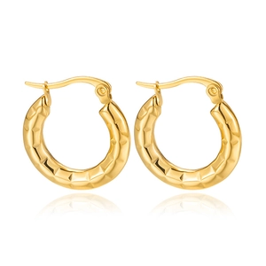 Macro view of gold-plated C-shape hoop earrings with geometric diamond-cut texture details