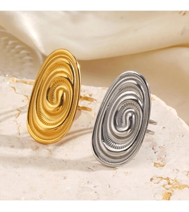 Macro detail of gold and silver chunky spiral rings on stone and silk background