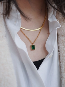 Close-up of double layer gold snake chain with a rectangular emerald green pendant