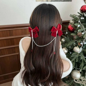 Red velvet bow hair clips with pearl chain tassels on a young girl's hair