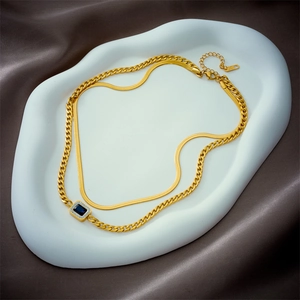 Collier double couche doré avec pierre précieuse bleue rectangulaire sur fond de satin