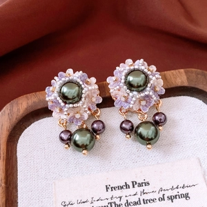 Detail of vintage flower stud earrings with purple resin petals and green pearls