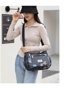 Floral crossbody bag detail featuring multiple zip pockets and navy waterproof nylon fabric