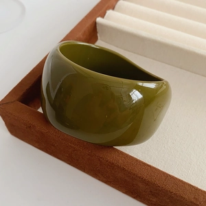 Close-up of olive green asymmetric resin wide ring on a premium velvet jewelry display