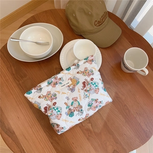 Quilted white cotton pouch with colorful teddy bear patterns on a rustic wooden table