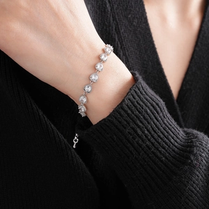 Close-up of heart zircon bracelet on black sweater cuff with silver extension chain