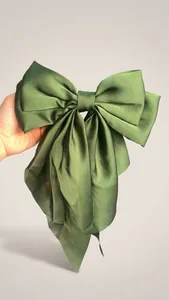Detailed view of large dark green satin bow hair clip with elegant long ribbons