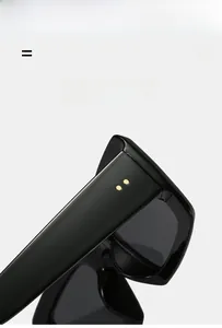 Detail of lightweight black rectangular sunglasses with golden rivets and elastic frame