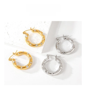 Detail showing gold and silver hoop earrings with clear rhinestones on stone background