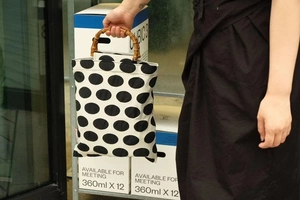 Macro detail of natural bamboo handle and bold black polka dot pattern on a stylish tote bag