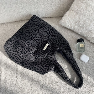 Close-up of leopard print tote bag with suede texture and side woven label detail
