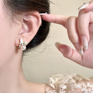 Detail of elegant gold butterfly earring with sparkling rhinestones and white pearl on ear