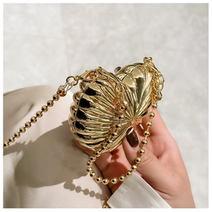 Macro shot of gold shell mini bag showing metallic shell texture and bead chain detail