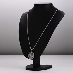 Silver oval Jesus pendant necklace with thorn texture on a black mannequin display