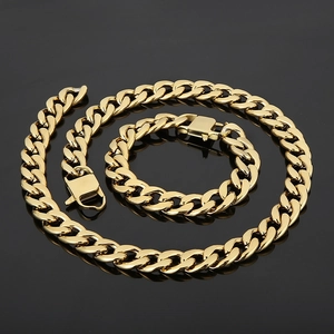 Détail d'un ensemble de chaînes gourmettes dorées avec texture métallique sur miroir noir