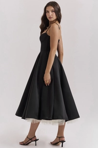 Detailed close-up of a black satin midi dress featuring a white tulle mesh underskirt