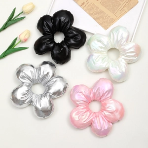 Floral hair scrunchies in black, silver, and iridescent colors with leather-like textures