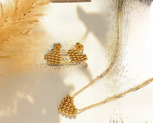 Close-up of a gold-plated heart-shaped jewelry set with beaded necklace and earrings