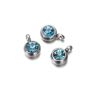 Close-up of three round silver charms with brilliant blue zircon insets for DIY jewelry