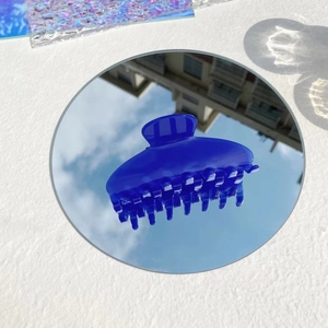 Close-up of a blue translucent claw clip on a mirror reflecting the bright sky