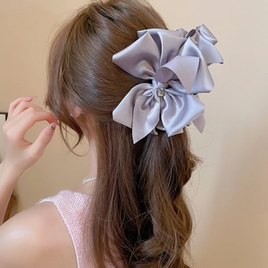 Detail of a large purple satin bow hair claw clip with a sparkling rhinestone center