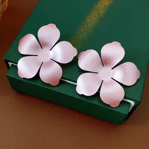 Minimalist matte pink flower stud earrings with five petals shown on a luxury jewelry box