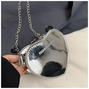 Close-up of metallic silver heart-shaped mini bag with chain strap and printed text