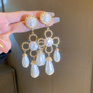 Close-up of vintage gold tassel earrings with teardrop pearls and twisted metal hoops