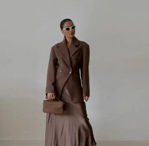Detail of high-waisted brown lapel blazer with double-breasted buttons and silk skirt