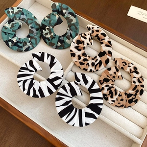 Detailed view of large fabric-wrapped hoop earrings in camo, leopard, and zebra prints