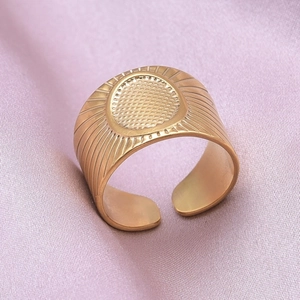 Macro shot of gold wide band ring with oval sunburst texture on silk background