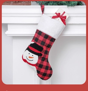 Detail of red and black plaid Christmas stocking with snowman embroidery on fireplace