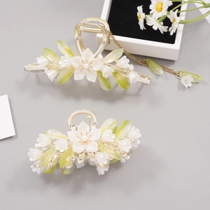Floral metal hair claw clips with white flowers, green leaves and tassel in elegant setting