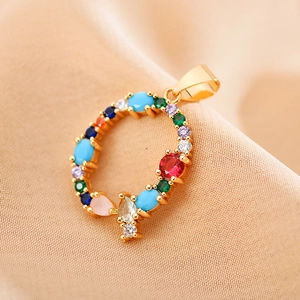 Close-up of gold round pendant with multi-colored zircon stones on beige fabric