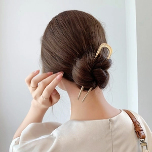 Minimalist U-shaped gold metal hair pin accessory for women styled in hair bun