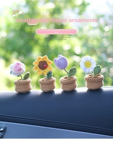 Close-up of four mini crochet flower pots including sunflower on a car dashboard