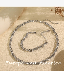 Silver chunky twisted rope chain necklace and bracelet set displayed on beige fabric