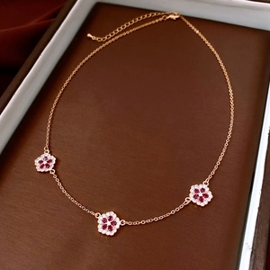 Macro shot of 18K gold-plated necklace with rose gold flowers and ruby-red stones