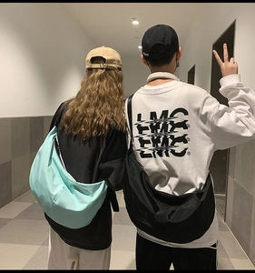Green and black nylon crossbody dumpling bags shown on models in a casual hallway scene